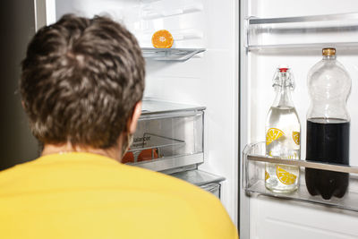 Rear view of man having food in kitchen
