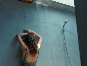 Rear view of woman standing against wall