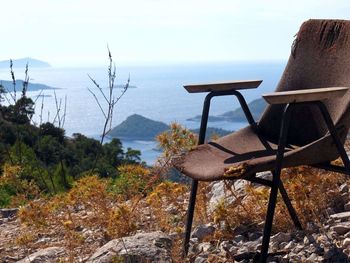 Chairs and table by sea against sky