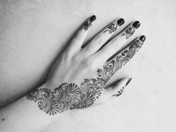 Cropped hand of woman with henna tattoo touching wall