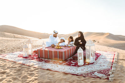 Happy family sitting carpet at desert