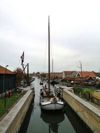 Sailboats on canal against sky