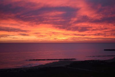 Scenic view of sea against dramatic sky during sunset