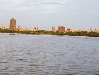 Sea by buildings in city against sky