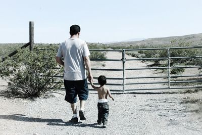 Rear view of man holding boys hand