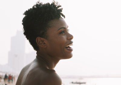 Portrait of smiling young woman looking away against sky