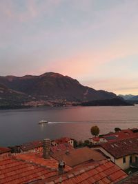 Early morning ferry on the lake at sunrise with view over terracotta rooftops on lake como in italy