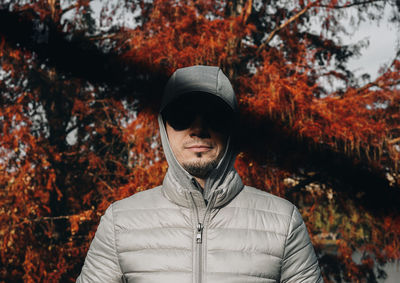 Man wearing hooded shirt while standing against trees