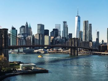 Brooklyn bridge and east river against sky in city