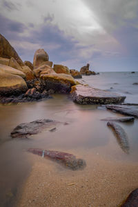 Rocks at sea against sky during sunset