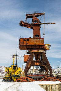 Abandoned drilling rig on snow against sky