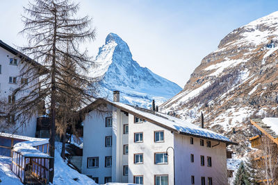 View of snow covered town and matterhorn mountain against sky during winter