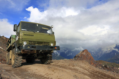 Truck on mountain against cloudy sky