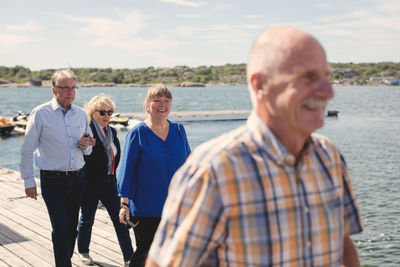 Happy senior male and female friends walking on pier during vacation