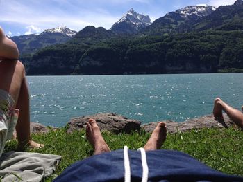 Low section of men relaxing at lakeshore