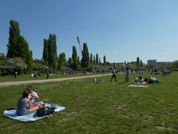 People relaxing in park against clear sky