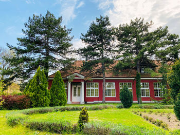 House and trees on field against sky