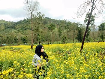 Woman and yellow flowering plants on field