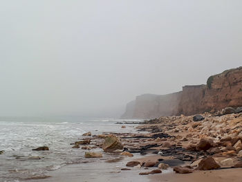 Rocks on beach against clear sky