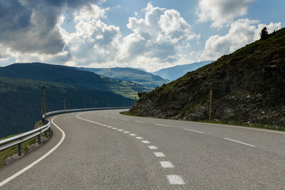 Empty road by mountains against sky