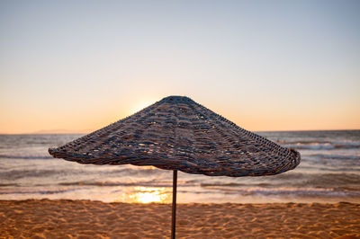 Parasol at beach against clear sky during sunset