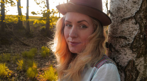 Portrait of woman in hat against tree