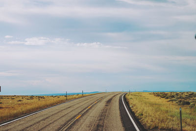 Road passing through land against sky