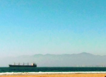 Boat sailing in sea against clear blue sky