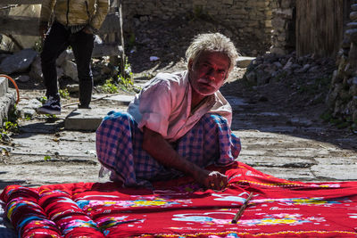 Portrait of old man sitting on street