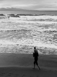 Full length of man walking on beach against sky