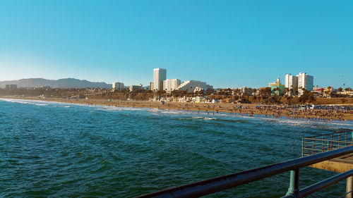 Sea and buildings against clear blue sky