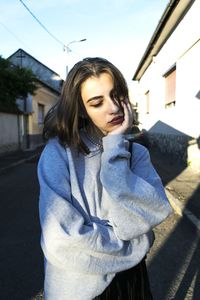 Young woman standing on street against building in city