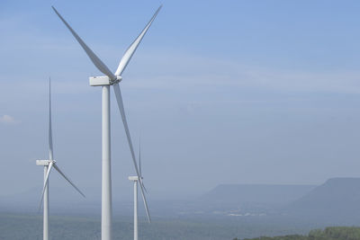 Wind turbines on landscape against sky