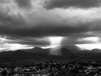 Sunlight streaming through storm clouds over landscape