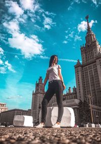 Low angle view of woman standing against buildings in city