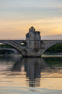 Arch bridge over river against sky during sunset