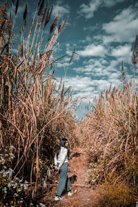 Rear view of woman standing on field against sky