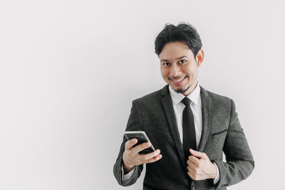 Portrait of smiling young man standing against white background