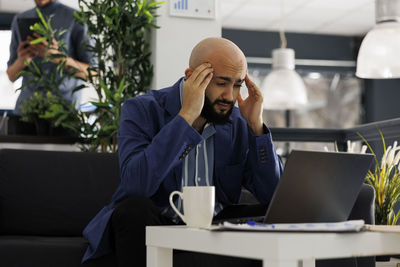 Side view of young woman using laptop while sitting in cafe