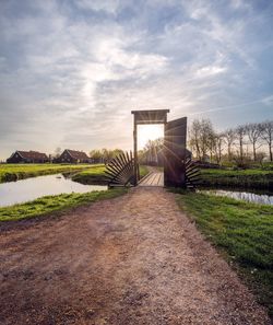 Footpath amidst field against sky