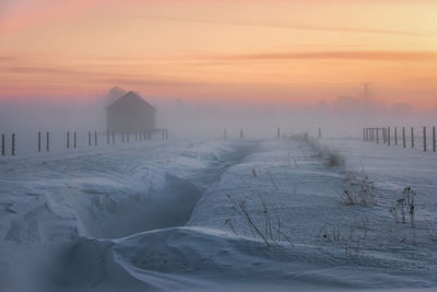 Scenic view of snow covered land against sky during sunset