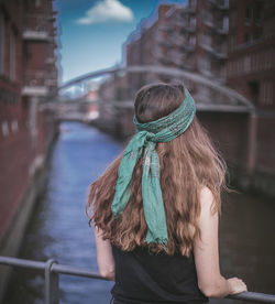 Rear view of woman standing by railing in canal