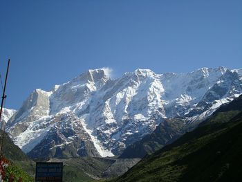 Low angle view of snow mountain against clear blue sky