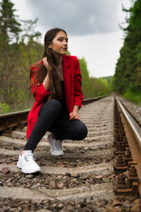 Young woman sitting on railroad track