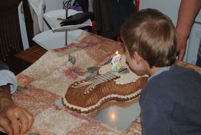 High angle view of boy blowing birthday candle on cake at home