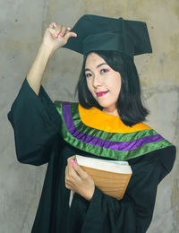 Portrait of a smiling young woman holding camera while standing outdoors