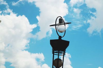 Low angle view of weather vane against cloudy sky