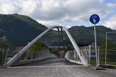 Road sign on bridge against sky
