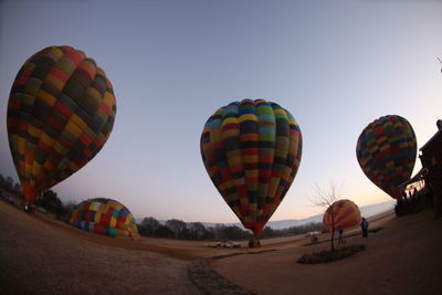 Low angle view of colorful hot air balloons on landscape against sky