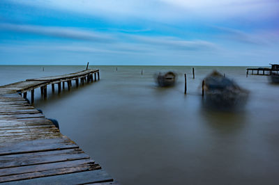 Wooden pier over sea against sky